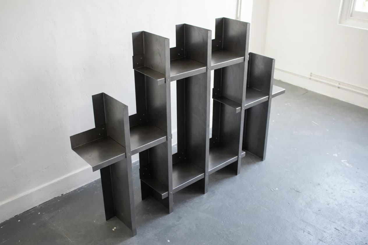 A tall folded-steel shelving study with staggered compartments, viewed from above.